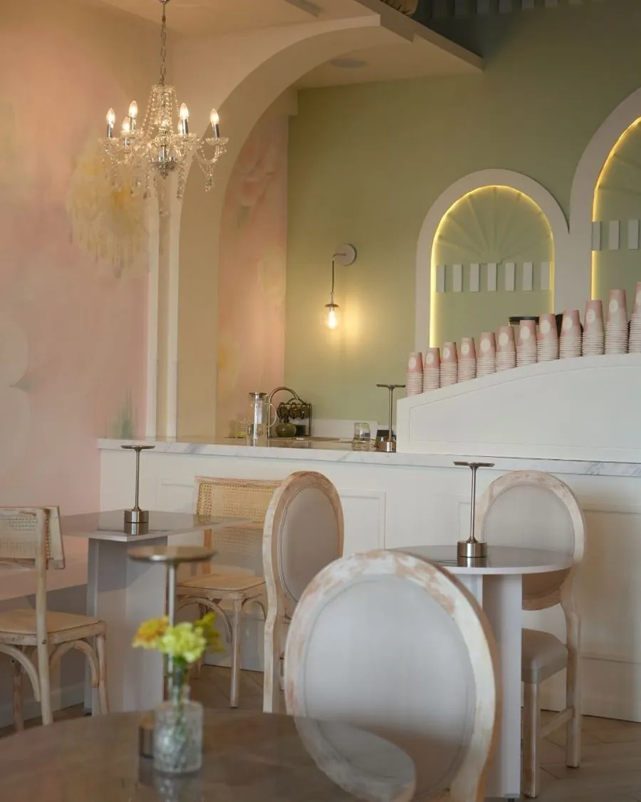 Salón con mesas, sillas claras y mural floral rosa