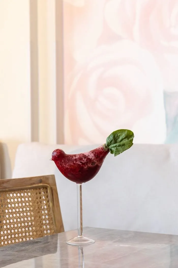 Bebida de frutos rojos en copa con forma de pájaro